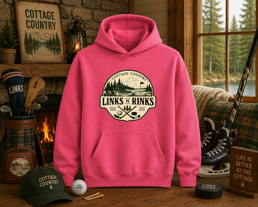 Charity Pink hoodie with 'Cottage Country Links N' Rinks' logo in a cozy cabin setting.